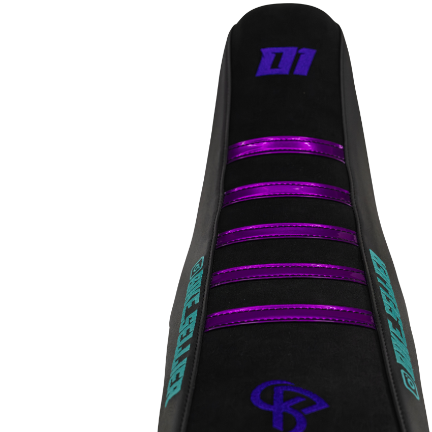 Gros plan sur une housse de selle cross BKS noire à bandes violettes brillantes, numéro 01 et monogramme brodés en violet