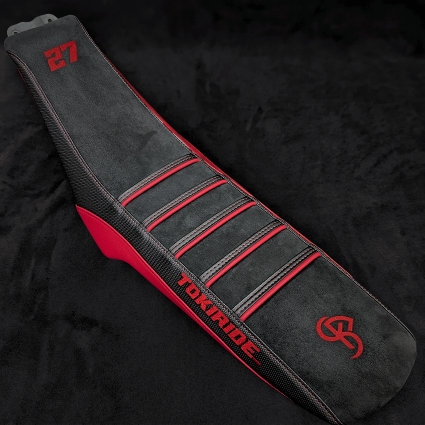 Housse de selle BKS gris anthracite et rouge à nervures, brodée, posée sur un velours noir