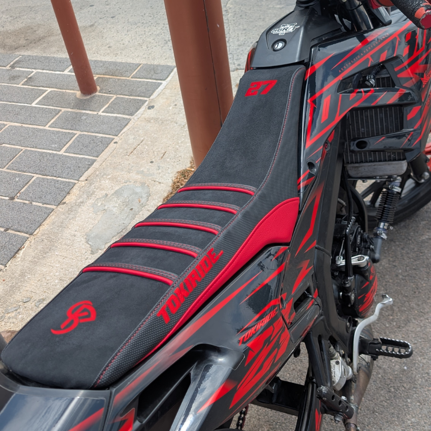 La même Rieju MRT 50 au même endroit, équipée de la housse de selle BKS en daim noir à nervures rouges, brodée 27 et TOKIRIDE