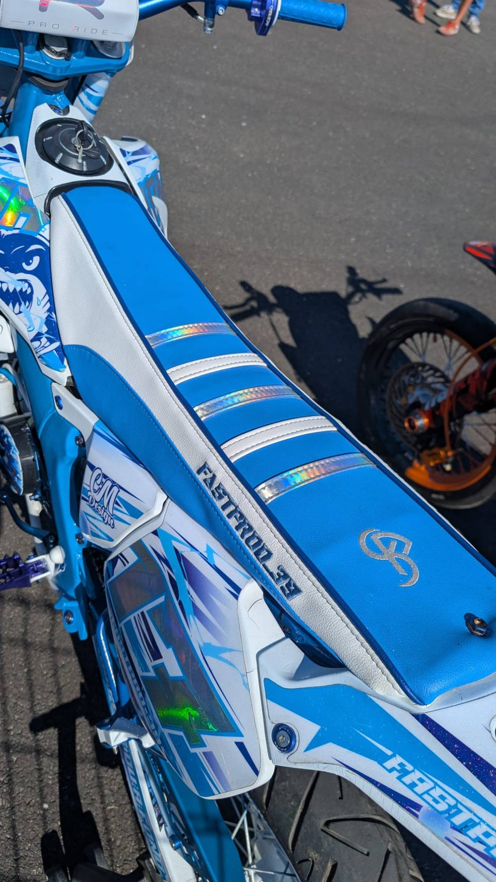 Moto 50 bleue et blanche équipée d'une housse de selle FUSION bleue et blanche à bandes holographiques