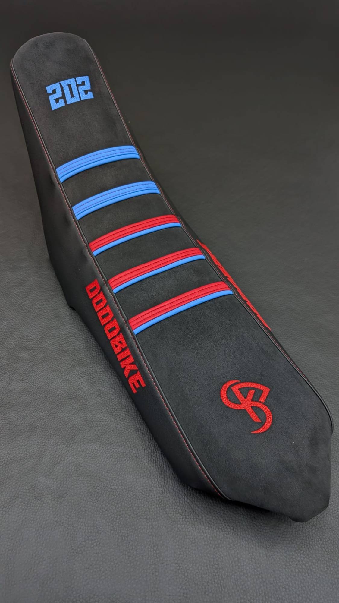 Housse de selle FUSION noire à bandes rouges et bleues, numéro et monogramme BKS brodés, photo studio