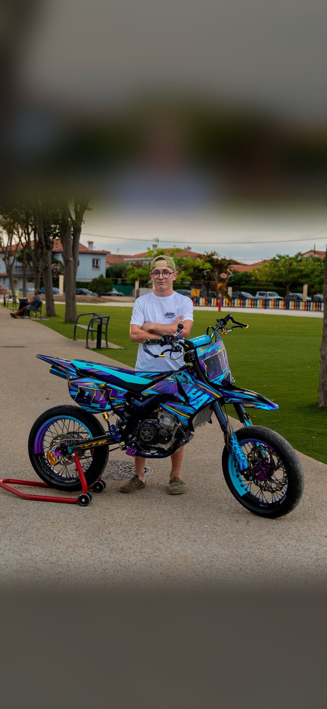 Supermotard turquoise et violet avec son pilote, housse de selle BKS en gros plan et vue de dessus brodée BKS
